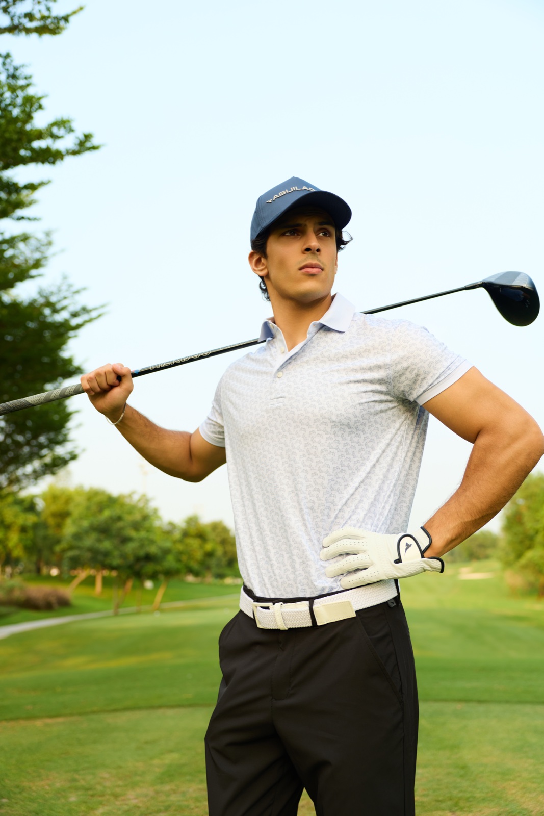 Golfer wearing a patterned white polo with a golf club over his shoulder