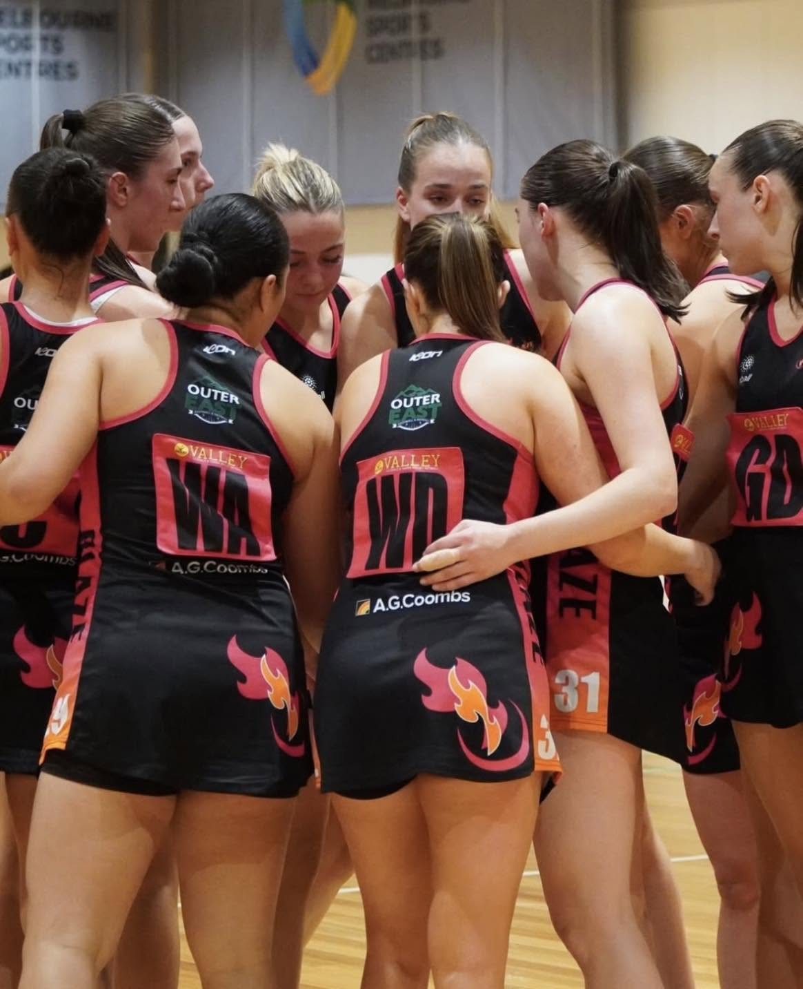 Netball players in matching ICON uniforms gather in a team huddle