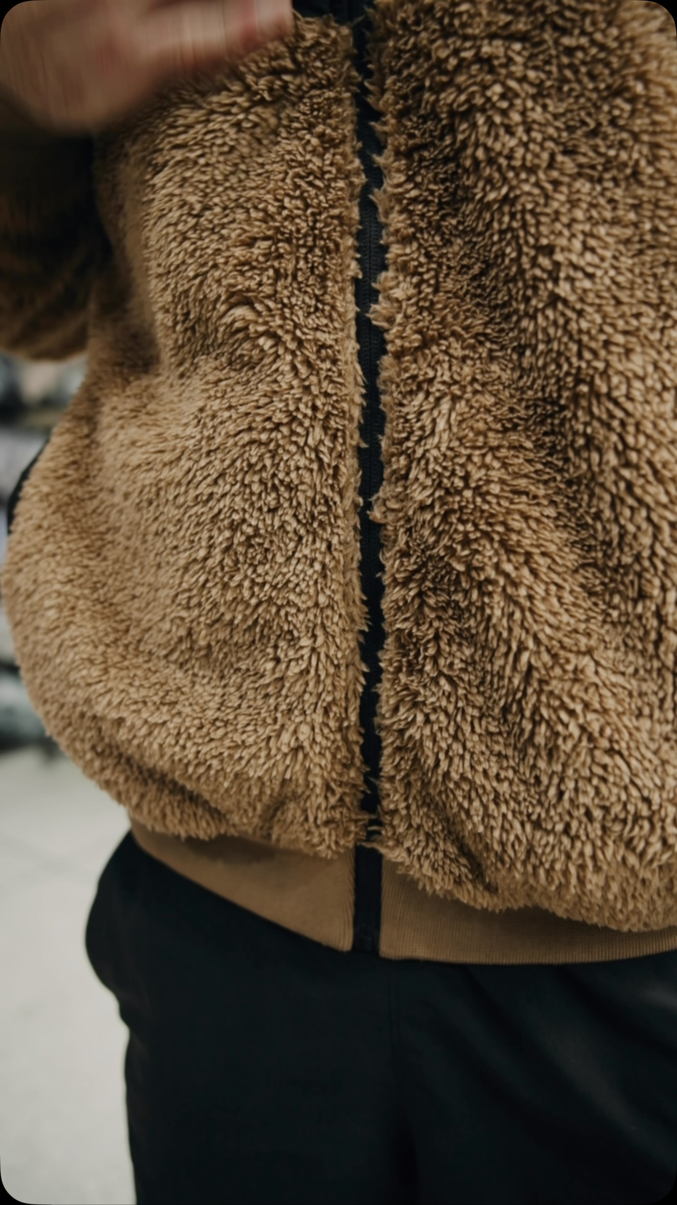 Close-up of brown sherpa fleece and a black garment zip